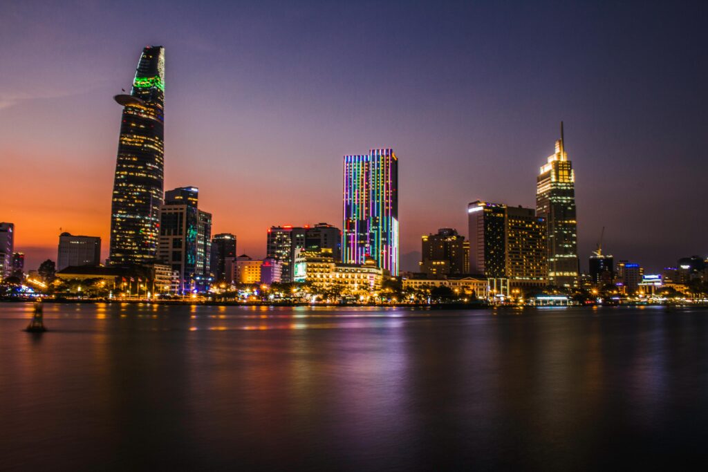 Ho Chi Minh City skyline at night, featuring illuminated skyscrapers and the Saigon River reflecting city lights during sunset in Vietnam