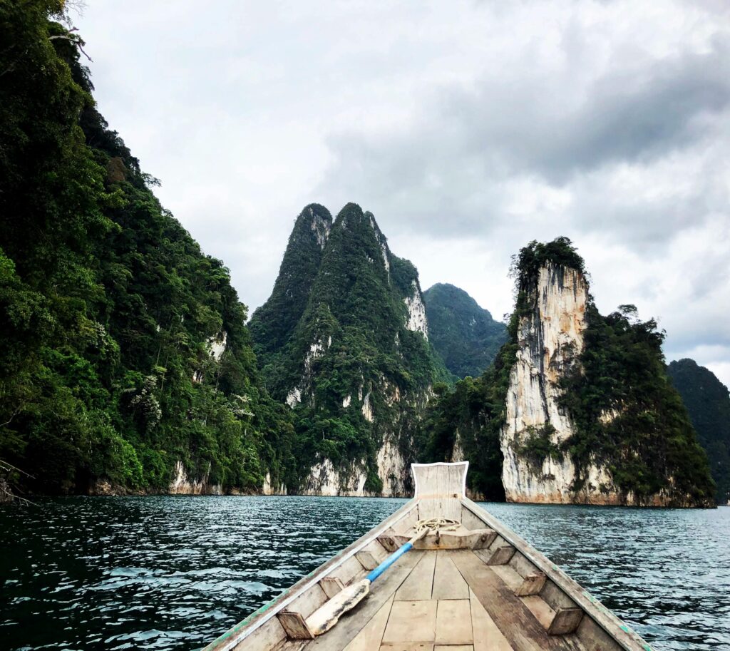 Tranquil scene of Cheow Lan Lake in Khao Sok National Park, Thailand, with emerald waters and towering limestone karsts surrounded by lush jungle