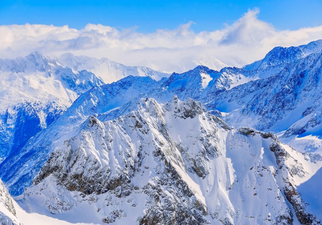 Panoramic view of rugged snow-covered peaks in the Alps with clear blue sky and dramatic winter mountain landscape