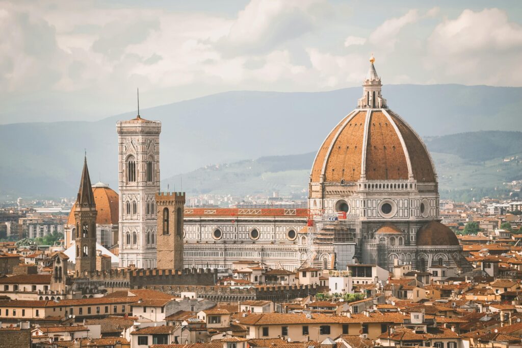 Aerial view of Florence Cathedral (Duomo di Firenze) with its iconic red-tiled dome, surrounded by historic buildings in Florence, Italy