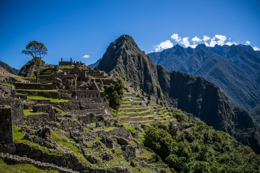 Panoramic view of Machu Picchu ancient Incan ruins with terraced hills and the Andes Mountains under a clear blue sky
