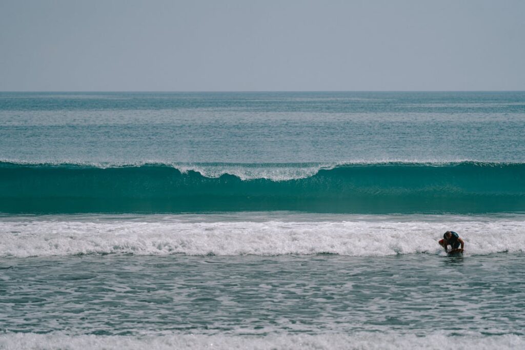 Surfer walking along the sea shore at Kuta Beach during golden hour in Bali, Indonesia