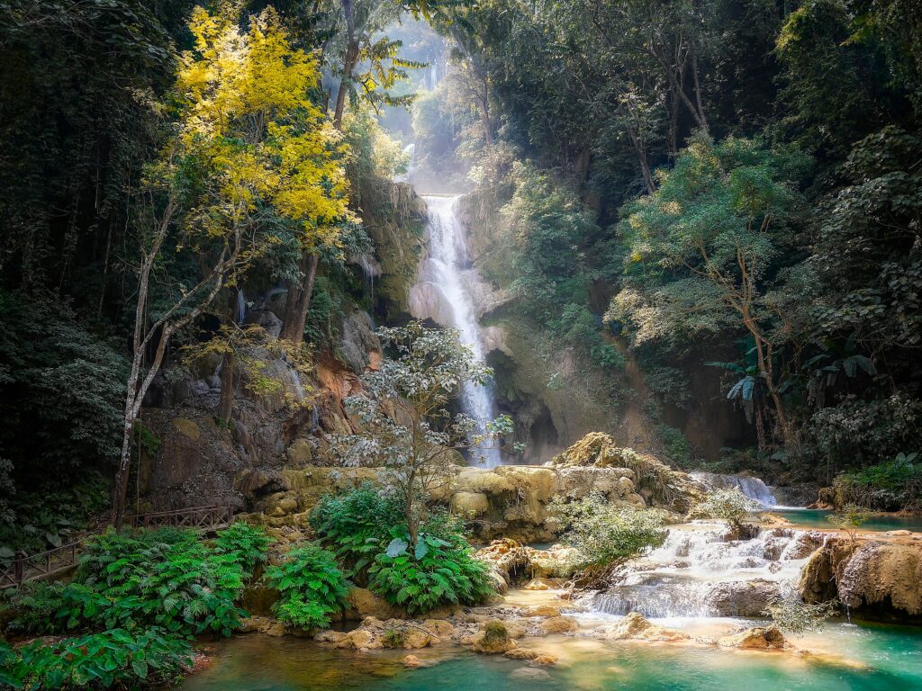 Scenic waterfall surrounded by turquoise pools and lush jungle in Luang Prabang, Laos, a popular eco-tourism destination