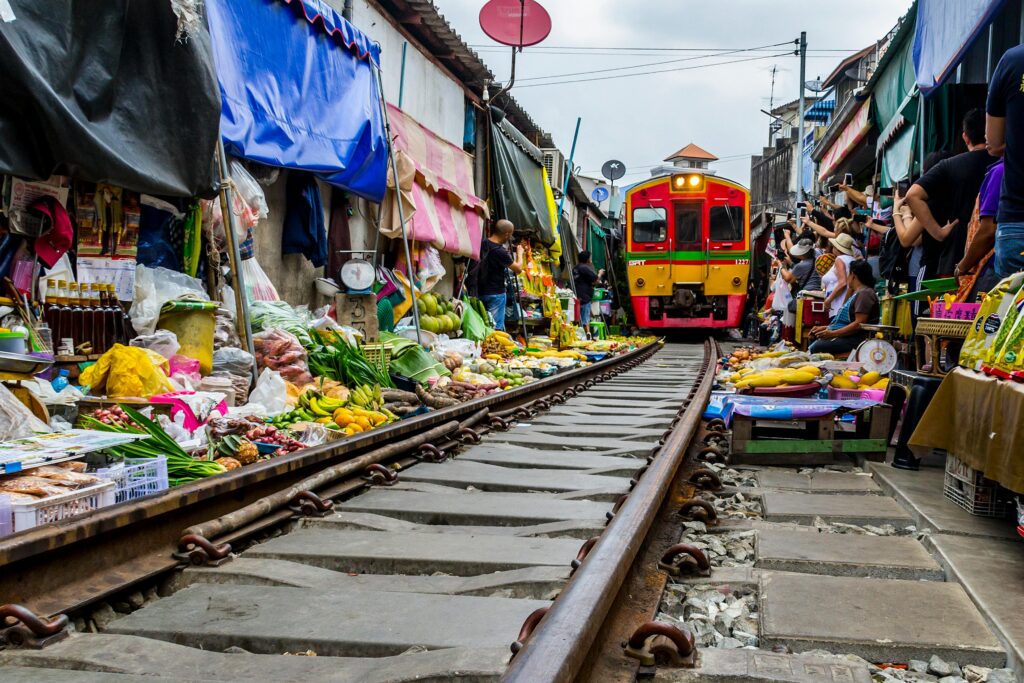 Unique experiences in Bangkok - Maeklong Railway Market with vendors retracting awnings for passing train