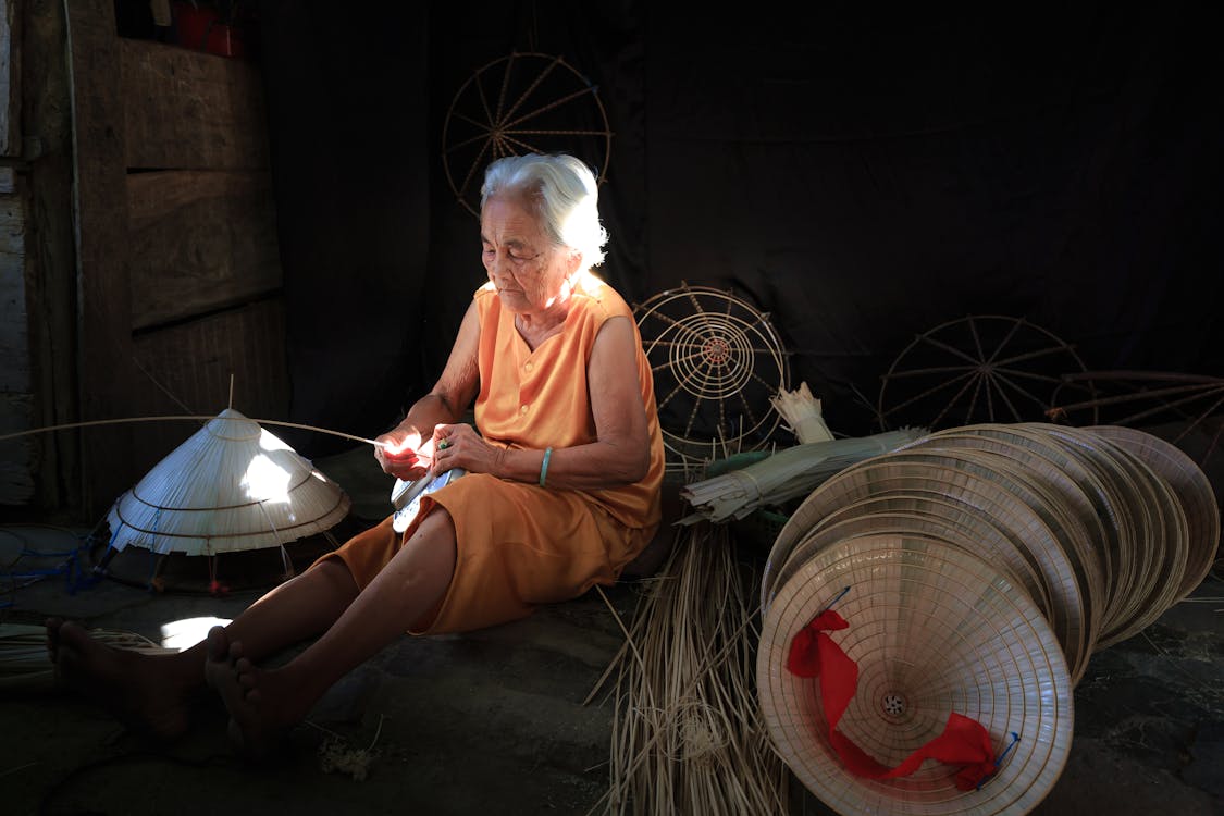 Vietnamese woman making a traditional Non La (conical hat) by hand using palm leaves and bamboo