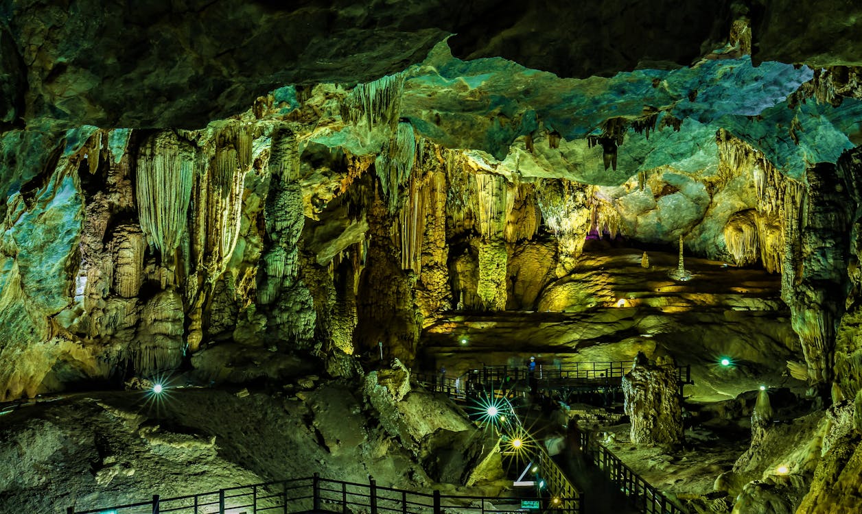 Interior view of Phong Nha-Ke Bang Cave in Vietnam, featuring stunning stalactites, stalagmites, and dramatic limestone formations illuminated by soft lighting.
