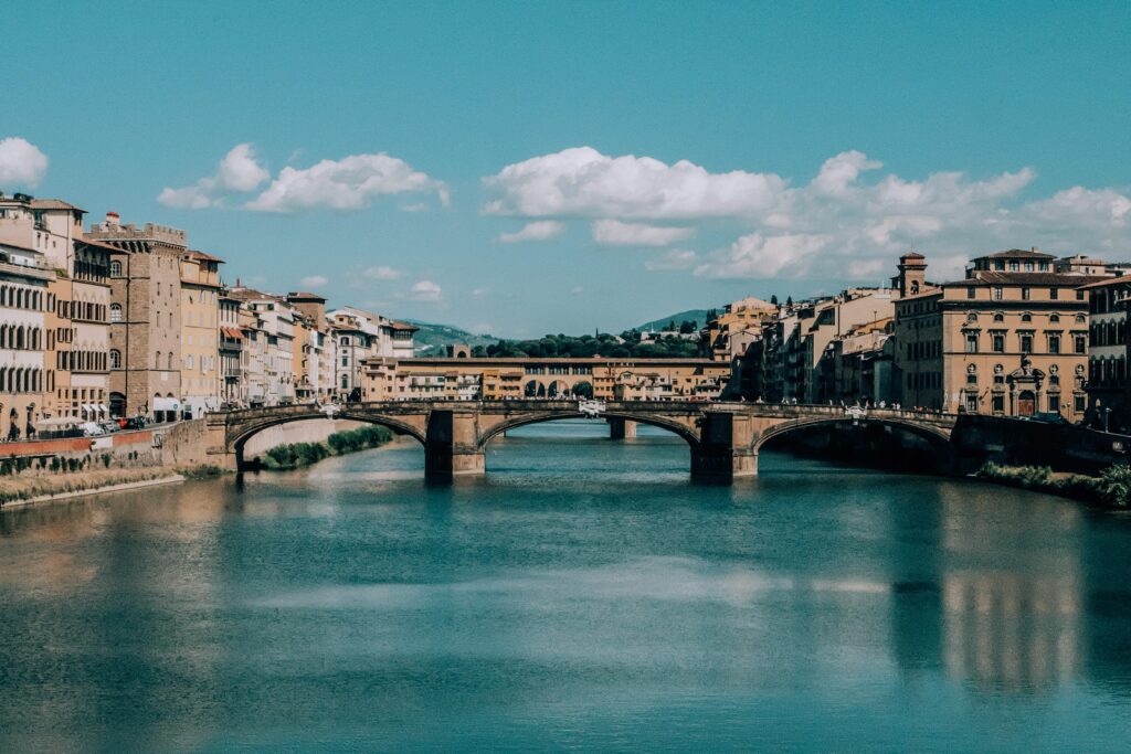 Ponte Vecchio bridge in Florence, Italy, connecting historic buildings over the Arno River under a clear blue sky
