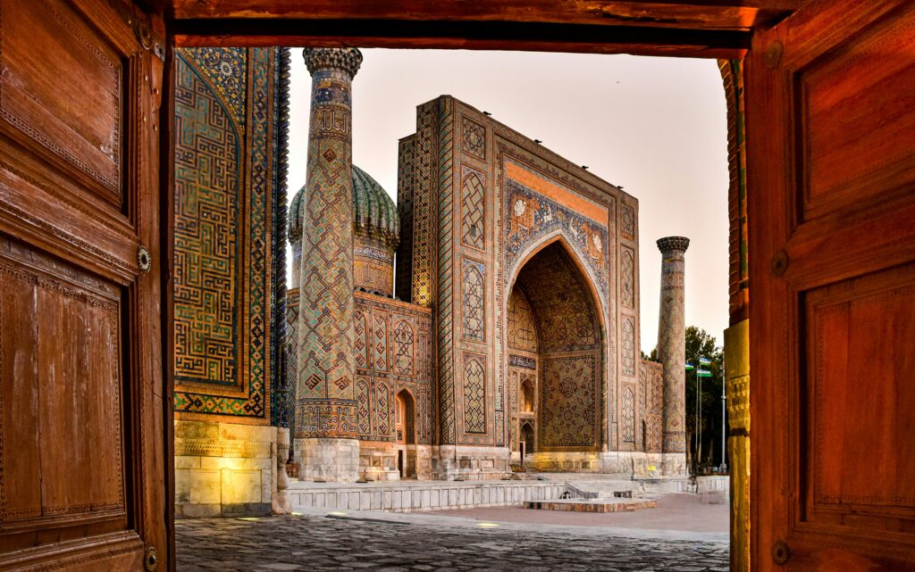 Registan architectural complex in Samarkand Uzbekistan viewed through wooden doors at sunset