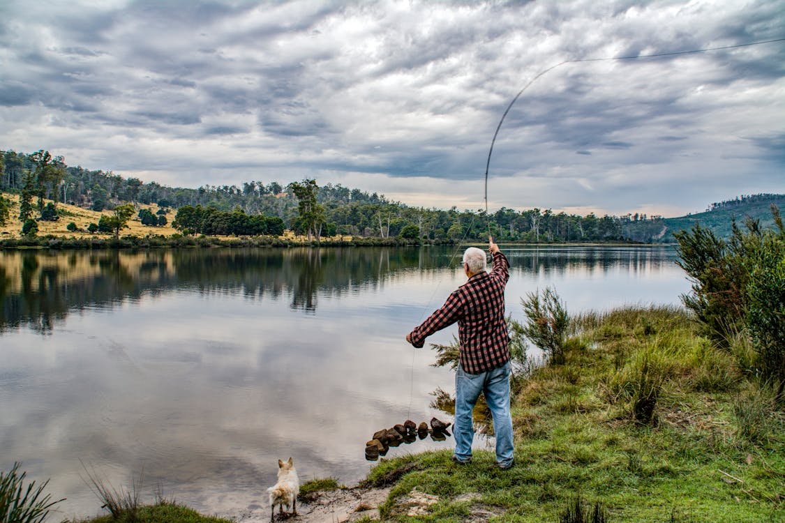 Ouse, Tasmania, with a peaceful atmosphere by the lake, featuring a man fishing in the calm waters.