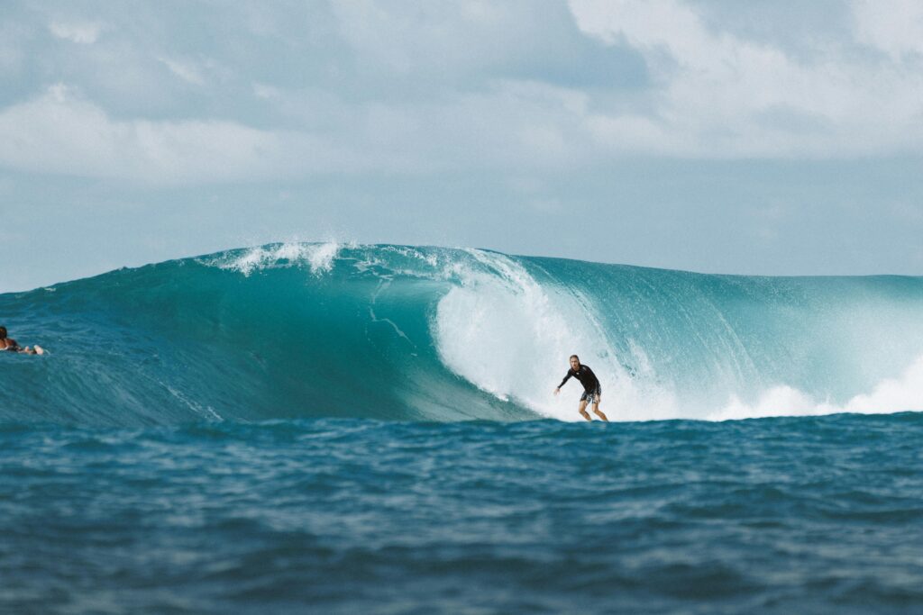 Surfer riding a powerful wave during Uluwatu surf season in Bali, Indonesia, with crystal-clear water