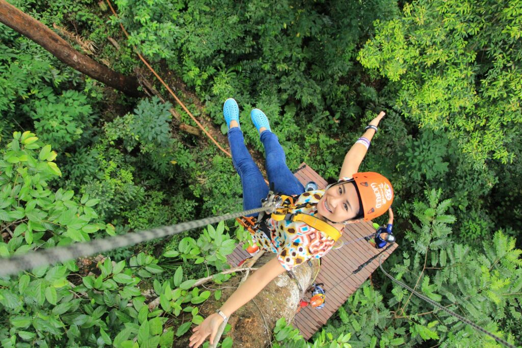 Traveler enjoying an exhilarating zipline adventure through the treetops, surrounded by lush jungle scenery in Thailand