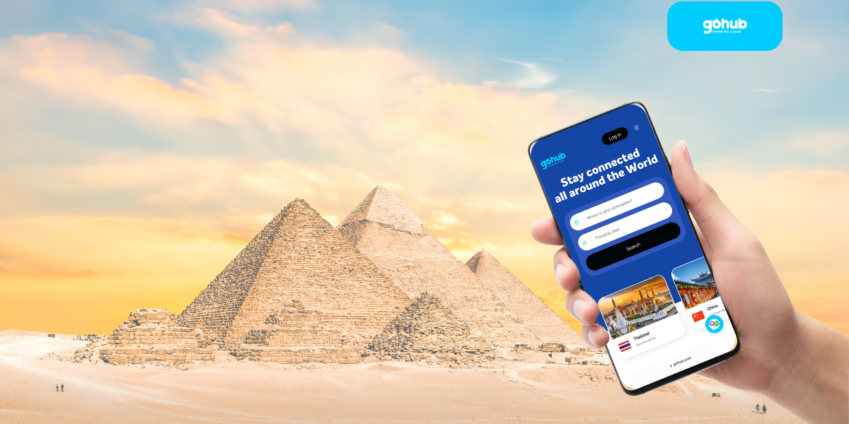 Traveler using Gohub eSIM app on smartphone in front of the Egyptian pyramids