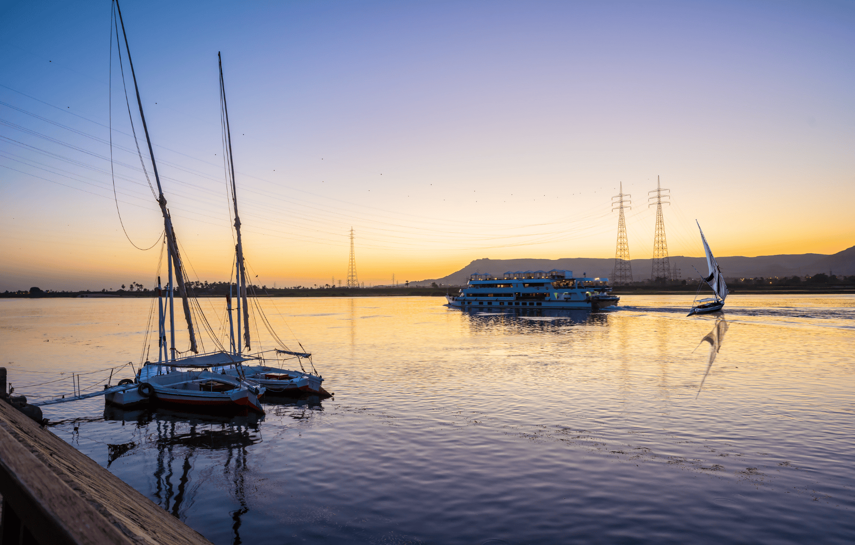 Traditional felucca boats sailing at sunset on the Nile River in Luxor, Egypt