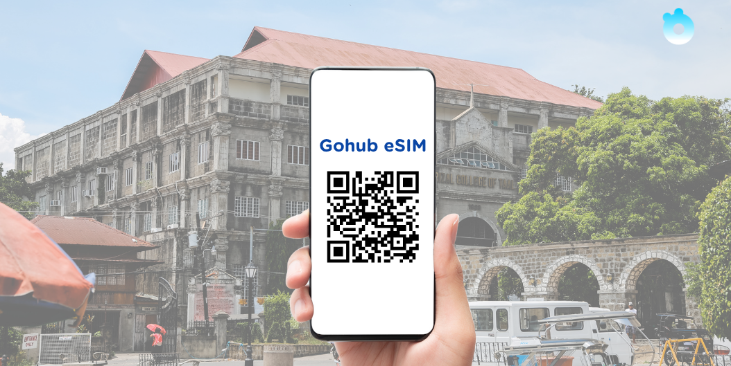 Hand holding a phone showing Gohub eSIM QR code in front of an old heritage building in the Philippines.