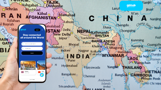 A traveler holding a phone with the Gohub eSIM app in front of a map of South and Southeast Asia.
